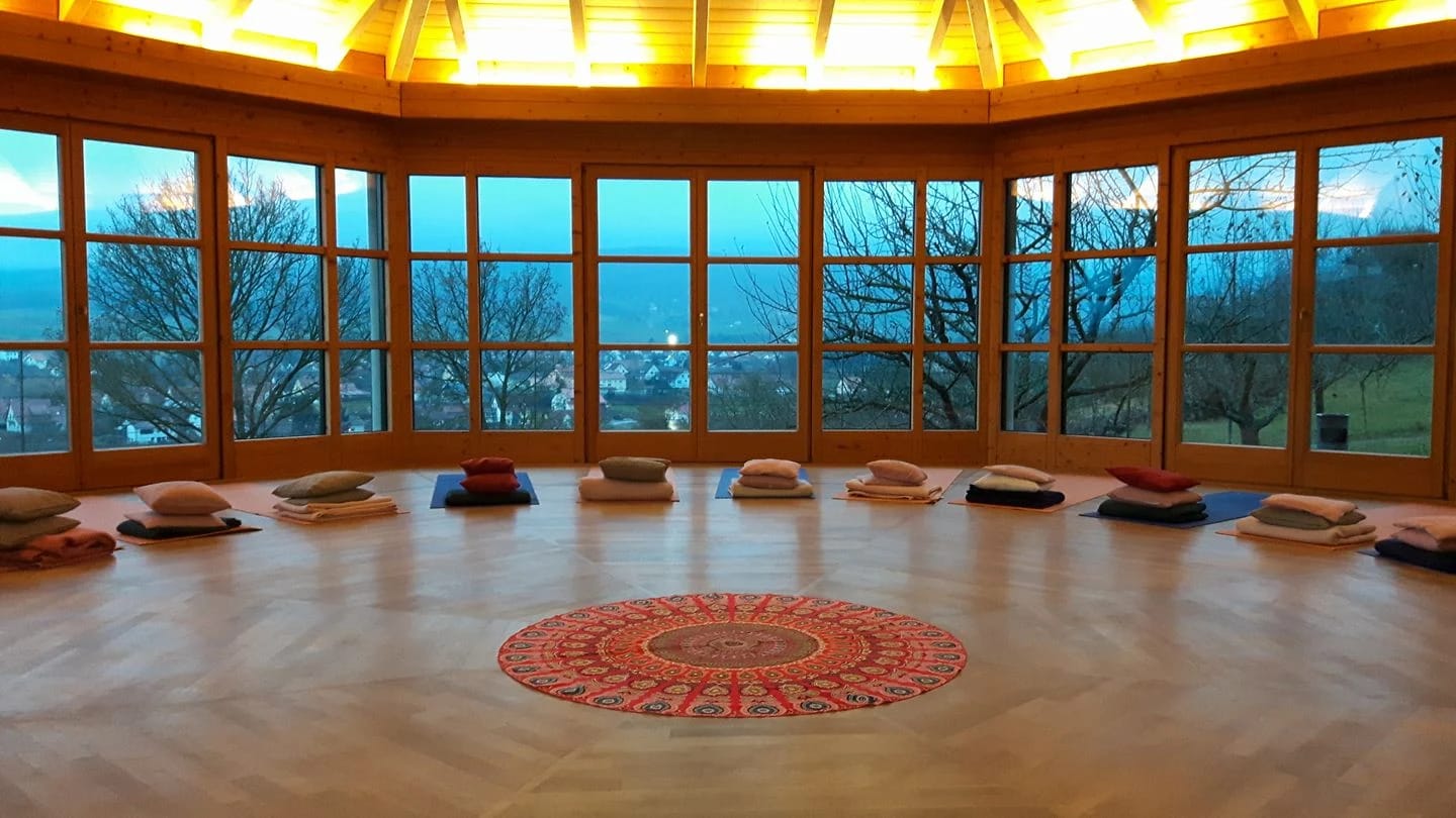 Runder Panoramaraum mit Meditationskissen im Kreis und umlaufender Fensterfront