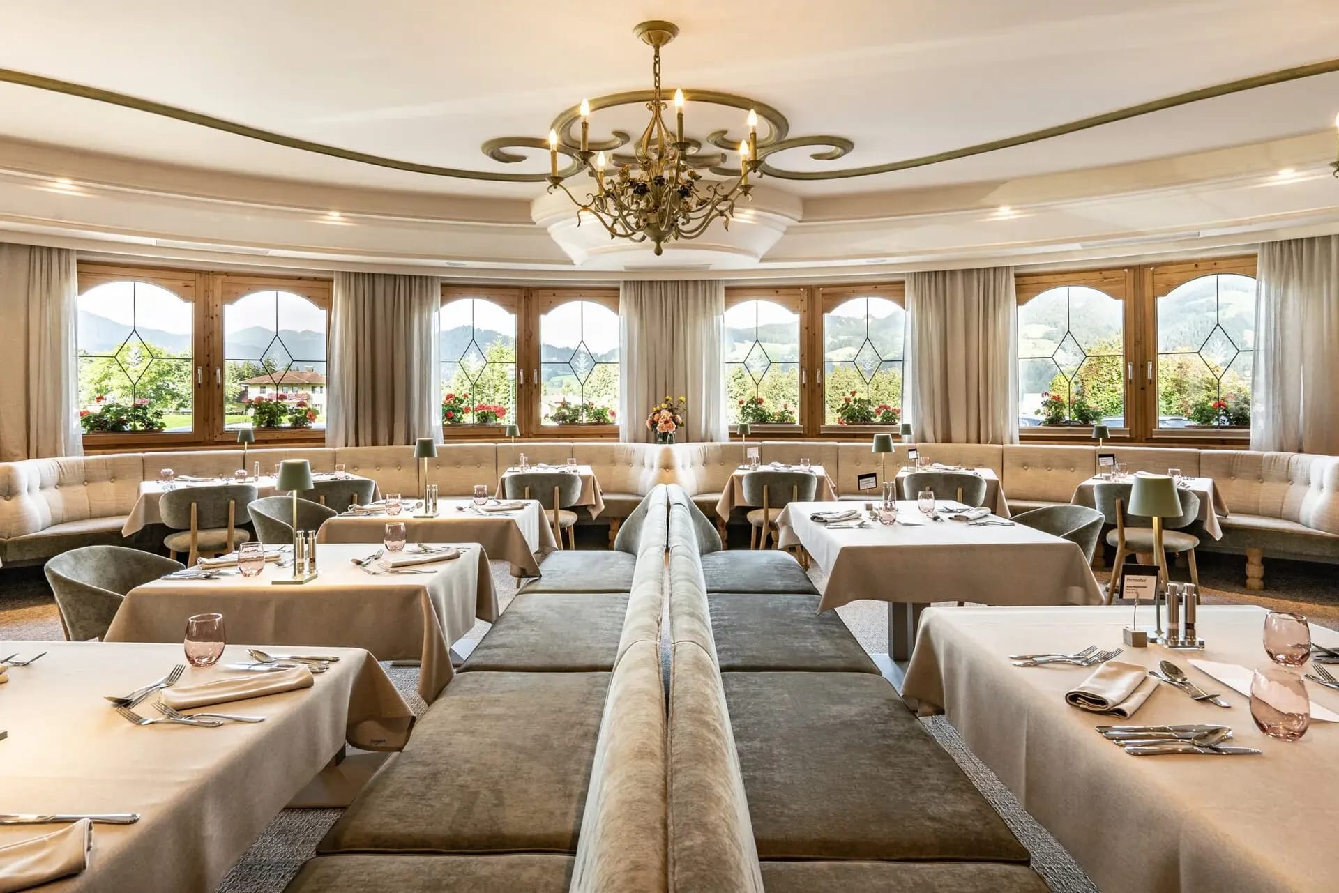 Moderner Restaurantbereich mit Rattanstühlen, Holzparkett und großen Fenstern zum Garten