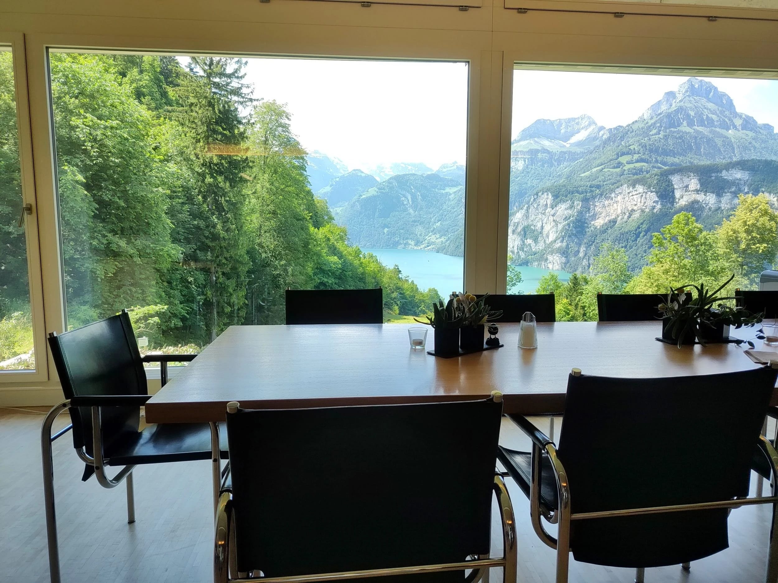 Tisch am Panoramafenster mit Stühlen und Blick auf See und Berge