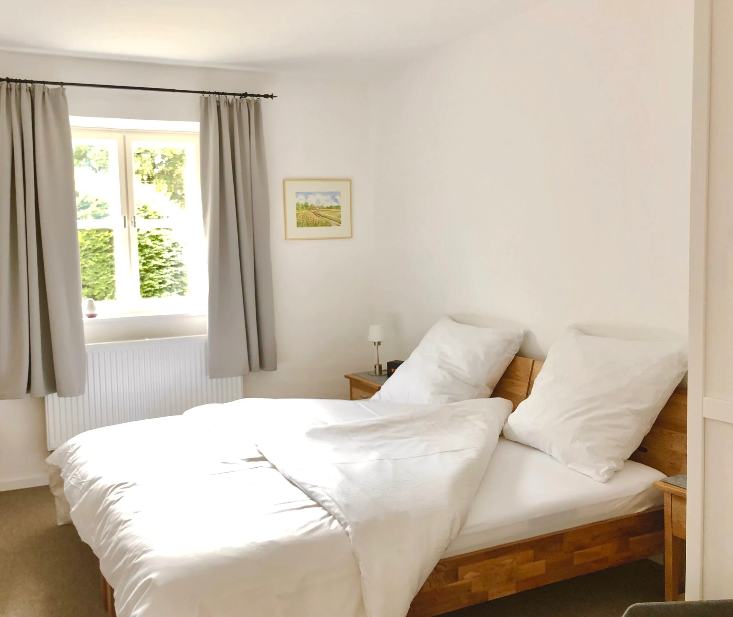 Schlafzimmer mit Doppelbett und Fenster mit Blick ins Grüne