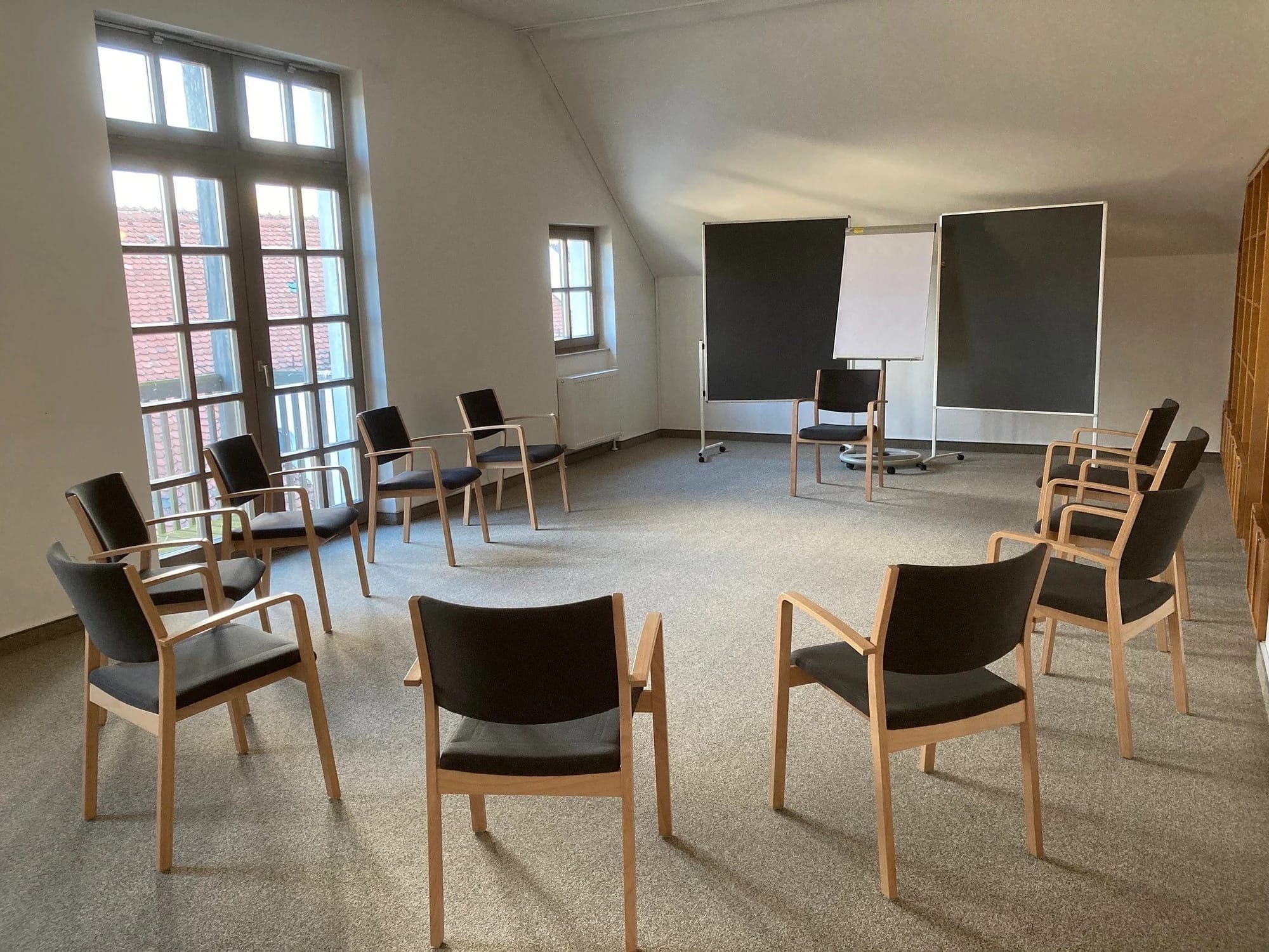 Heller Seminarraum mit Stuhlkreis, Flipchart und Balkontür