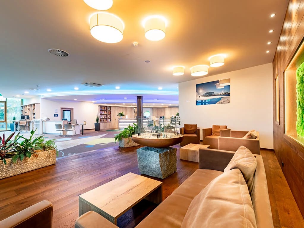 Hotellounge mit Holzboden, Polstersesseln und warmer Deckenbeleuchtung