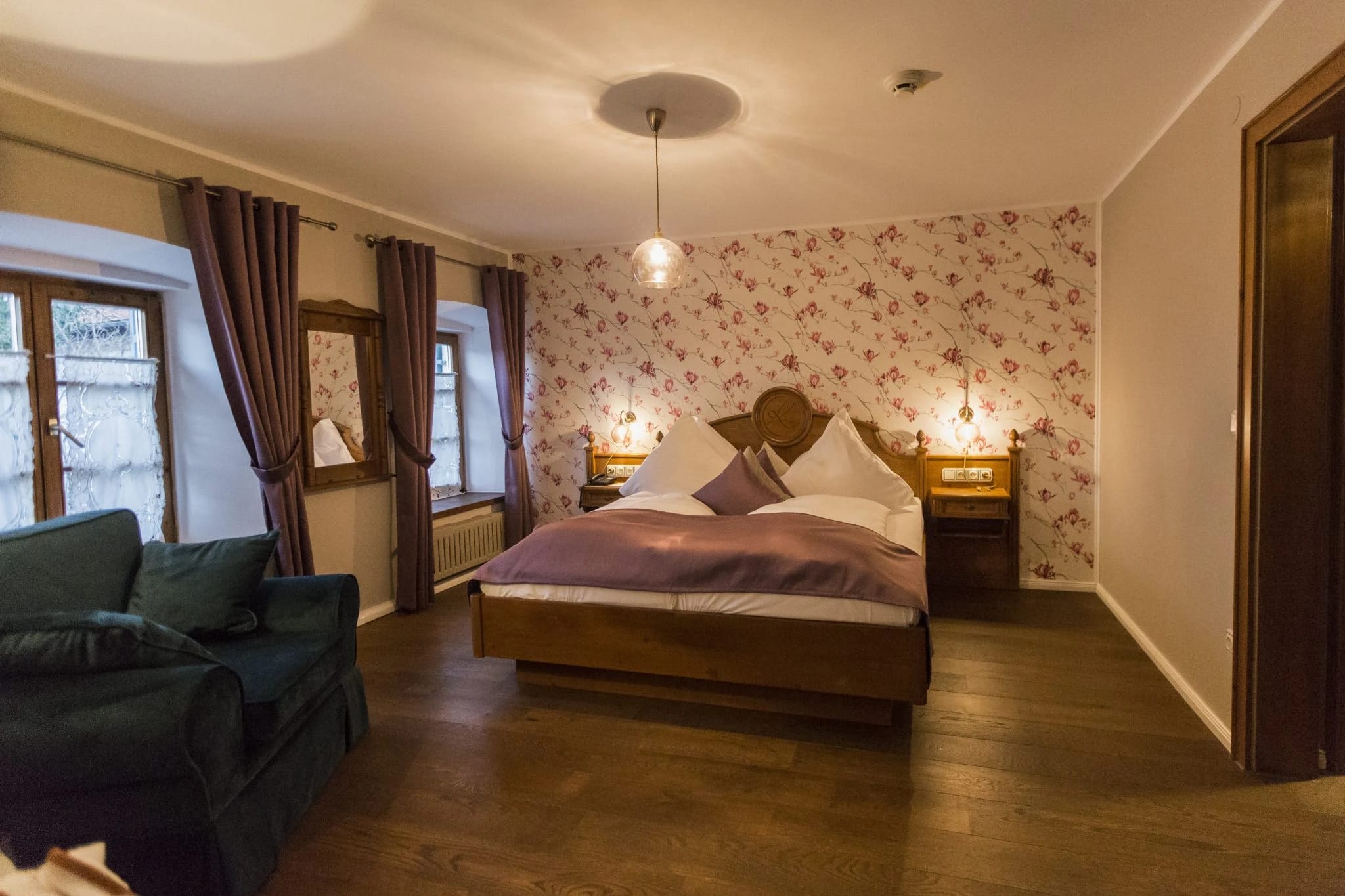 Zimmer mit Holzdoppelbett, blauer Sitzbank und Balkonzugang