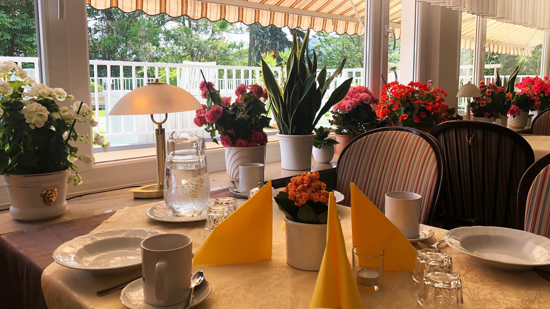 Speiseraum mit eingedeckten Tischen und Blumenschmuck am Fenster