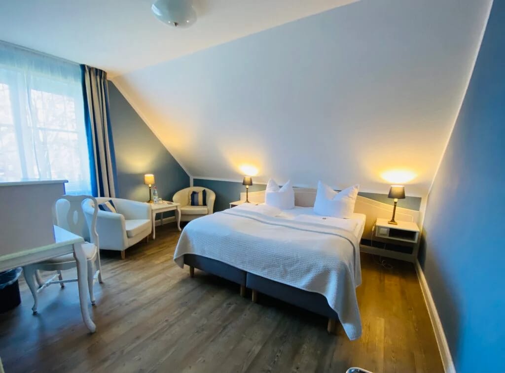 Zimmer unter Dachschräge mit Doppelbett und Sitzgruppe