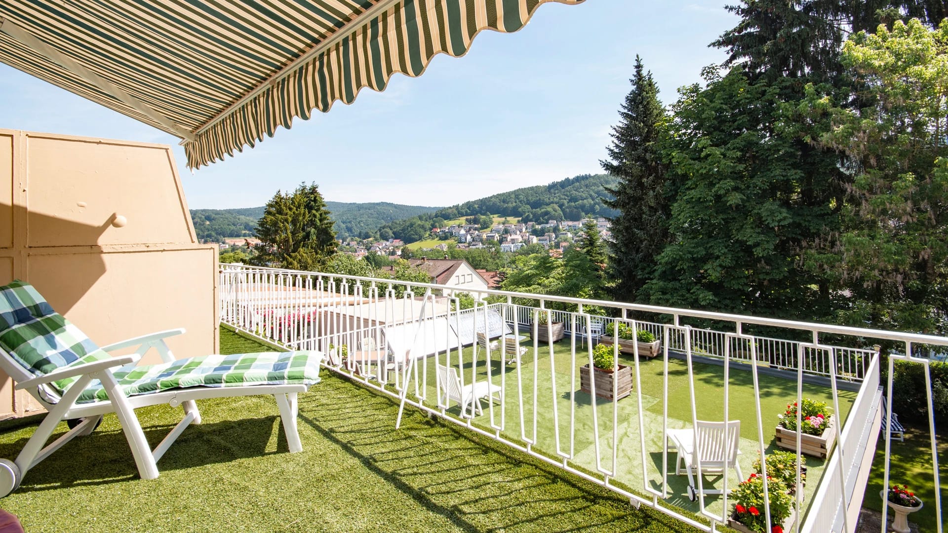 Terrasse mit Liegestuhl und Blick über den Ort und die Hügel