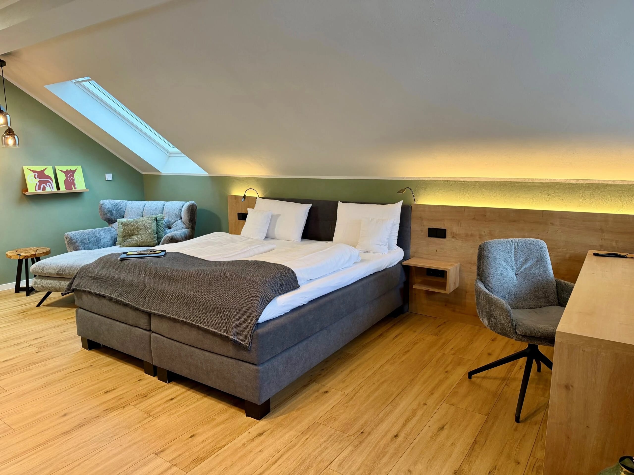 Modernes Dachgeschoss-Zimmer mit Boxspringbett und Holzboden unter Dachschräge