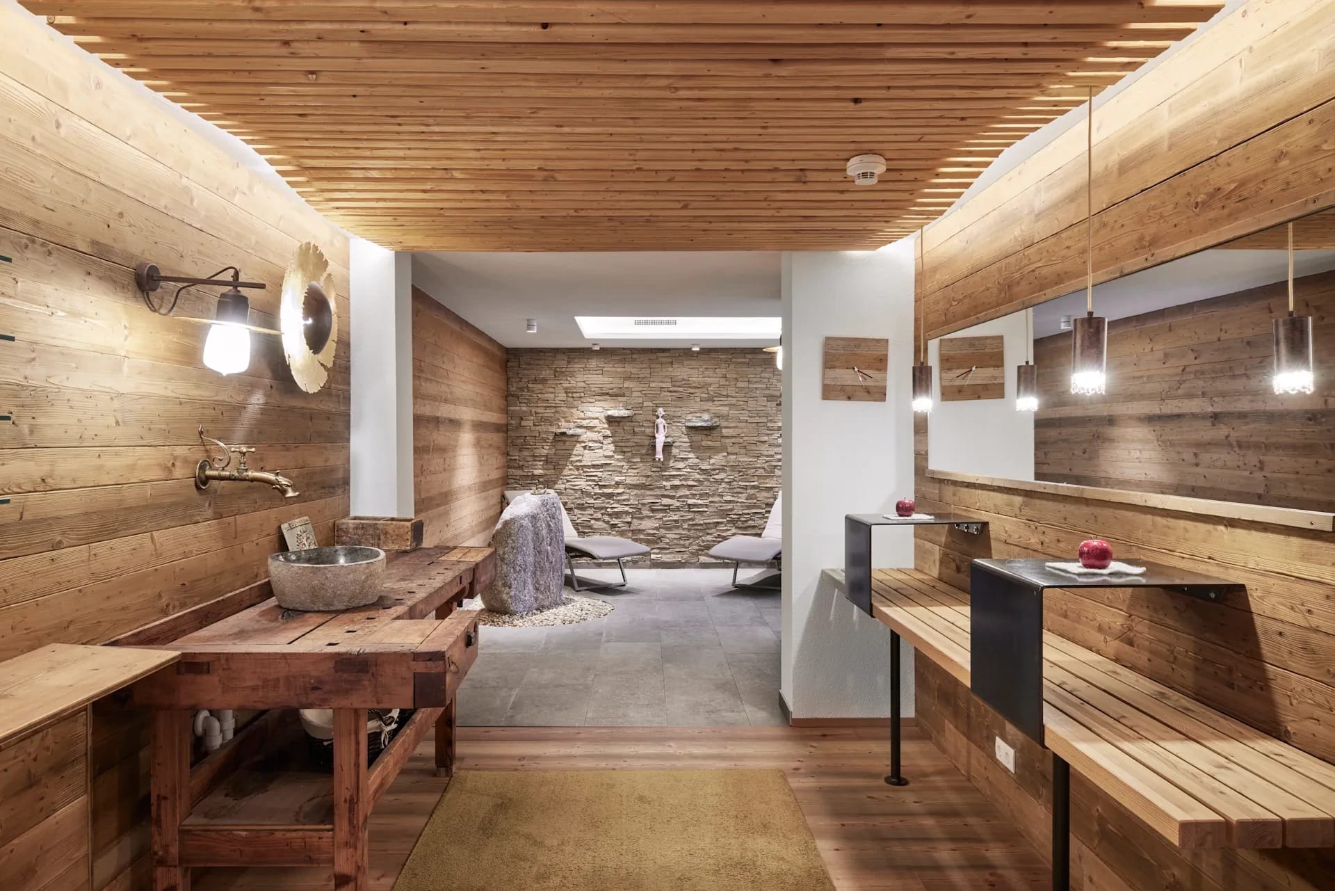 Wellnessbereich mit Holzvertäfelung, Steinwand und gemütlichem Ruhebereich