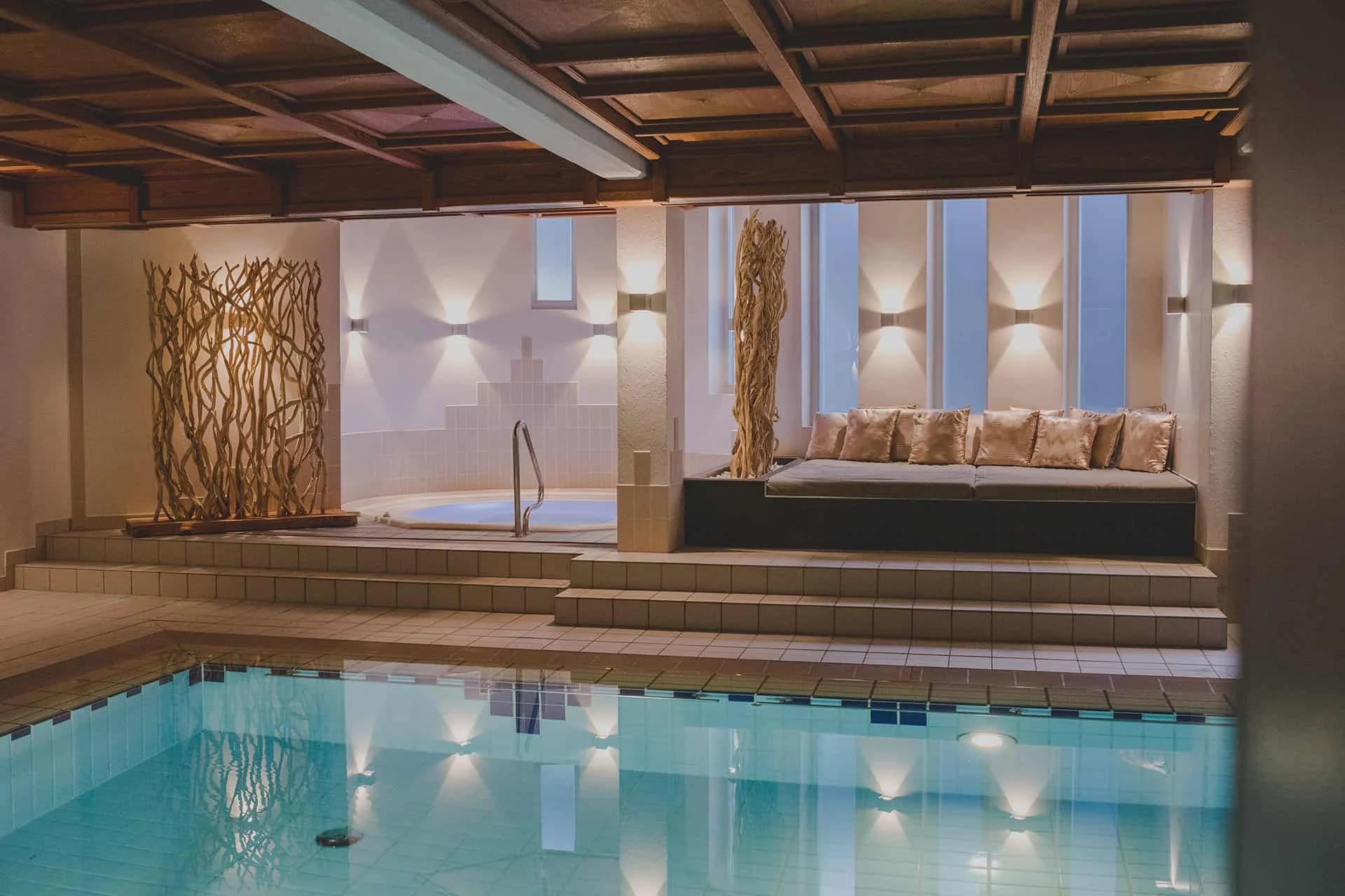 Innenpool mit Holzdecke und Ruheliege im Wellnessbereich