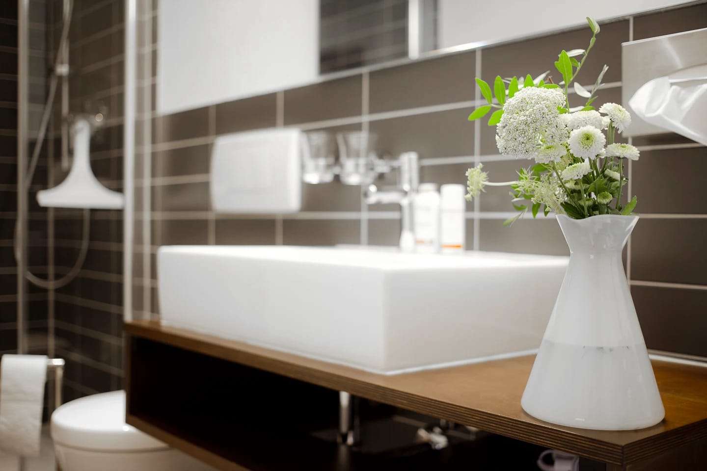 Modernes Badezimmer mit Waschbecken, grauen Fliesen und Blumenschmuck