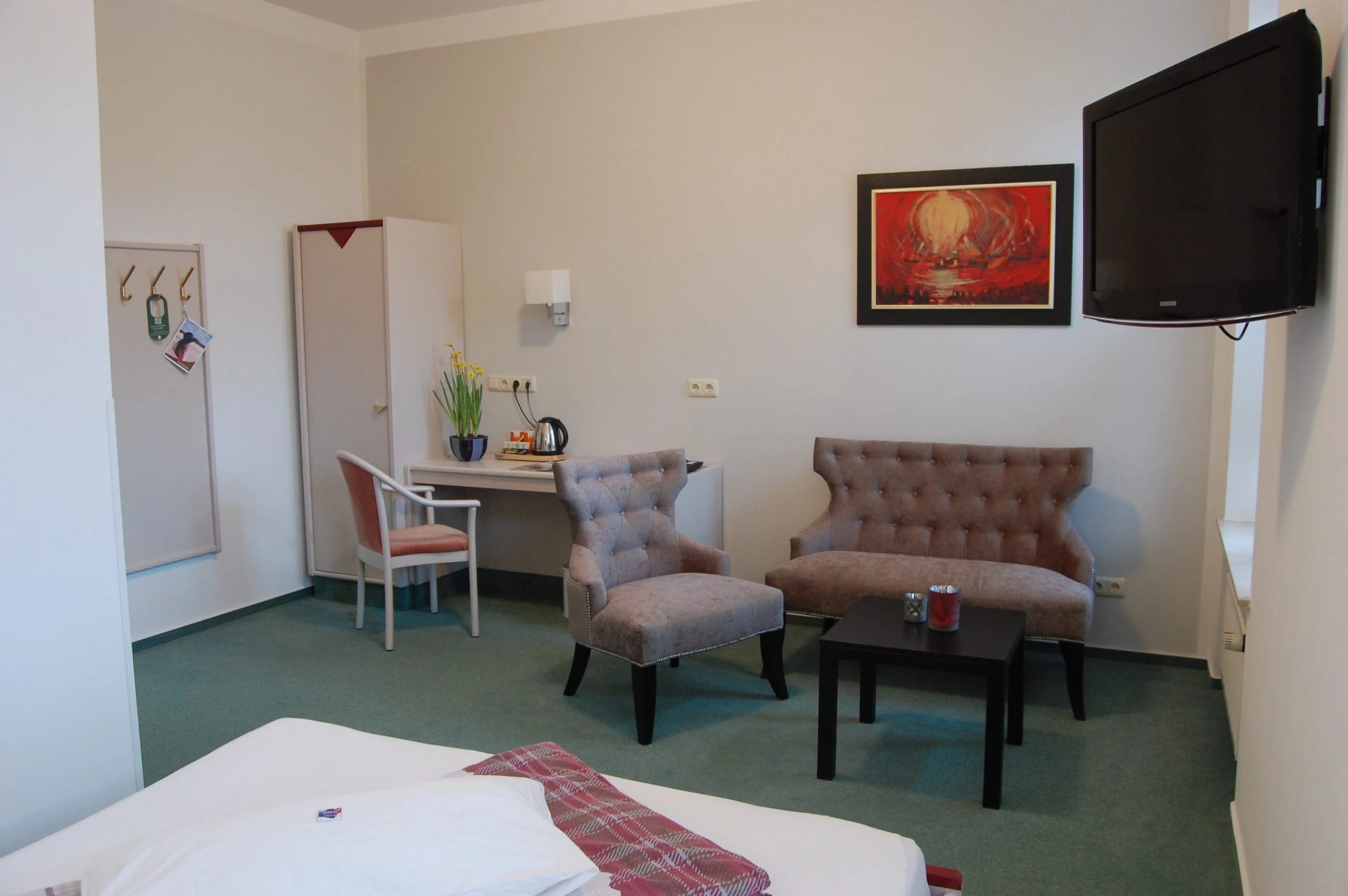 Zimmer mit Sitzecke aus zwei Sesseln und Sofa, Schreibtisch und Wandbild