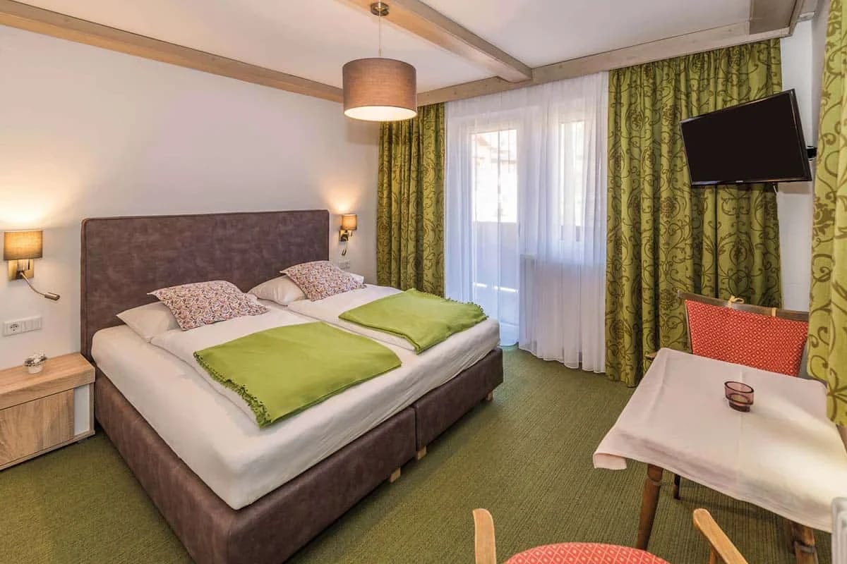 Doppelzimmer mit Bett und grünen Vorhängen im Hotel Wieshof