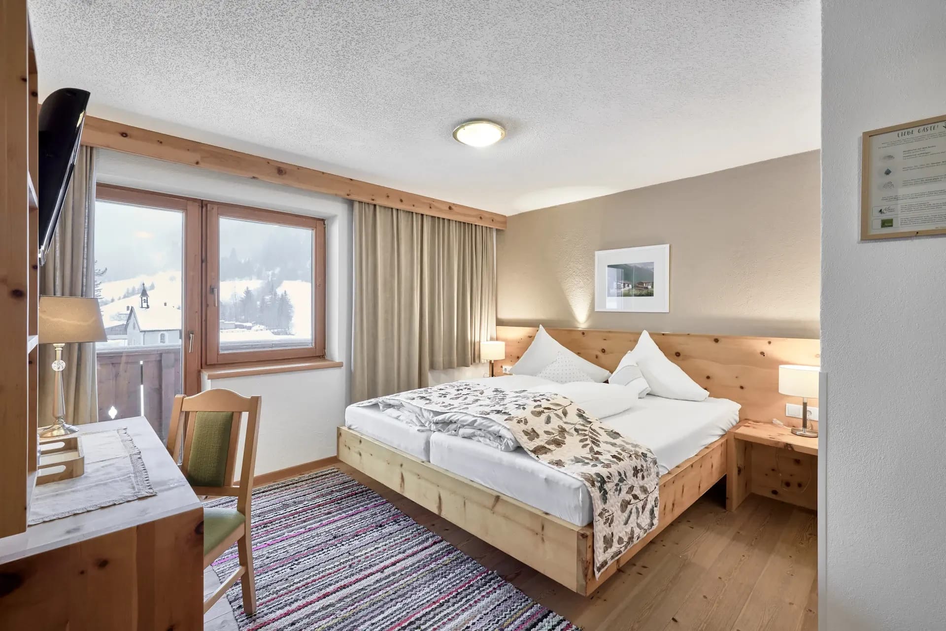 Doppelzimmer mit Zirbenholzbett, Sitzecke und Fenster mit Ausblick