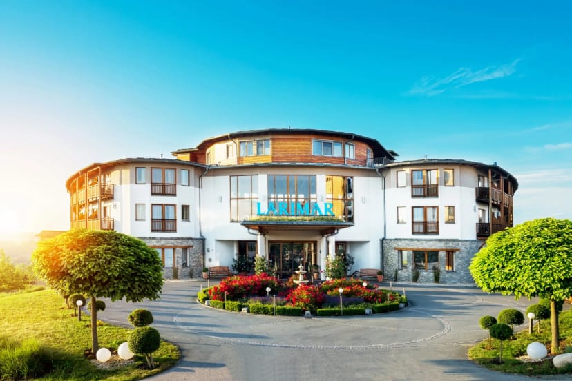 Frontansicht des Hotels mit Eingang, Springbrunnen und blauem Himmel