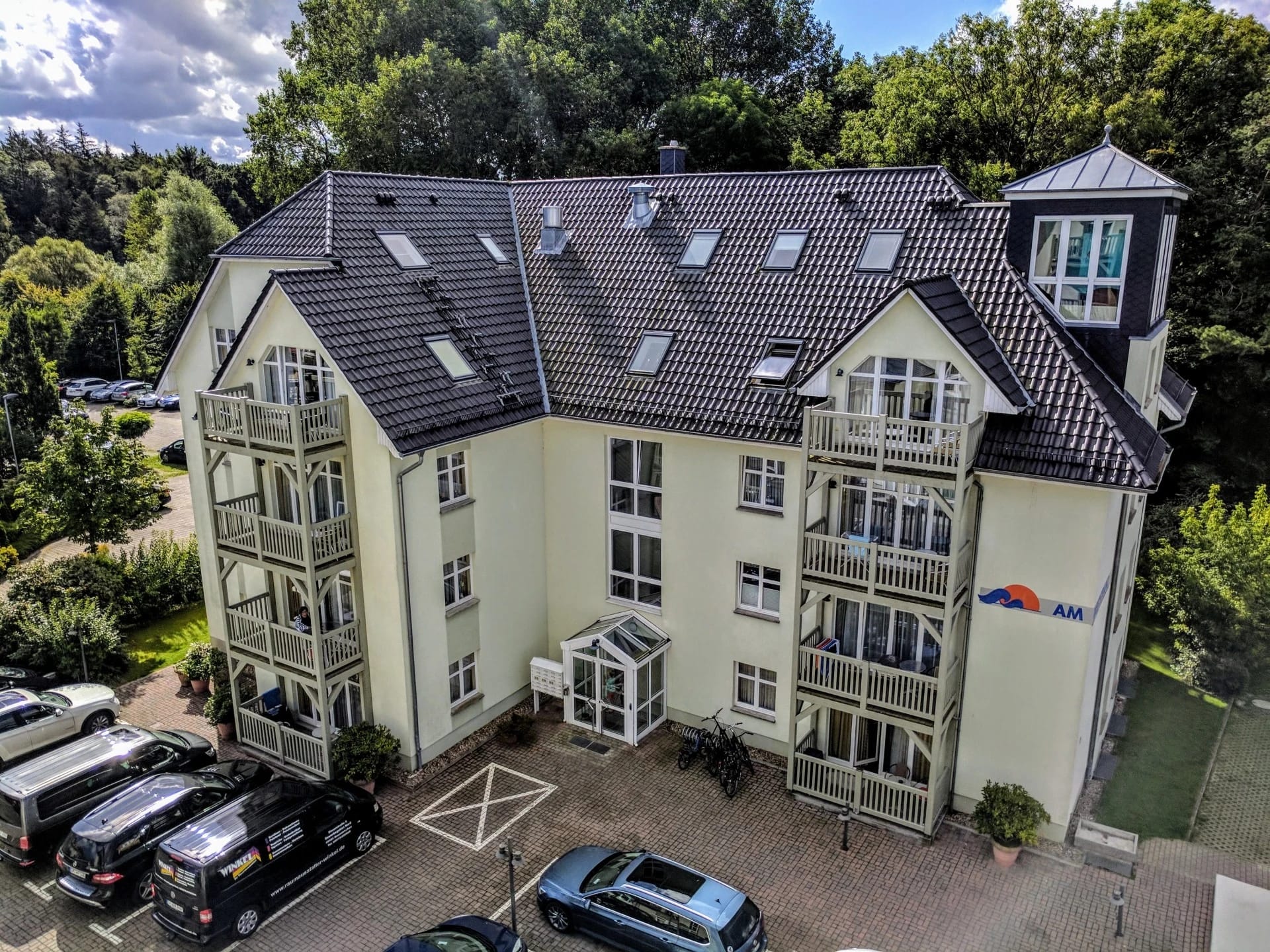 Erhöhte Ansicht des gelben Apartmenthauses mit Balkonen und Parkplatz