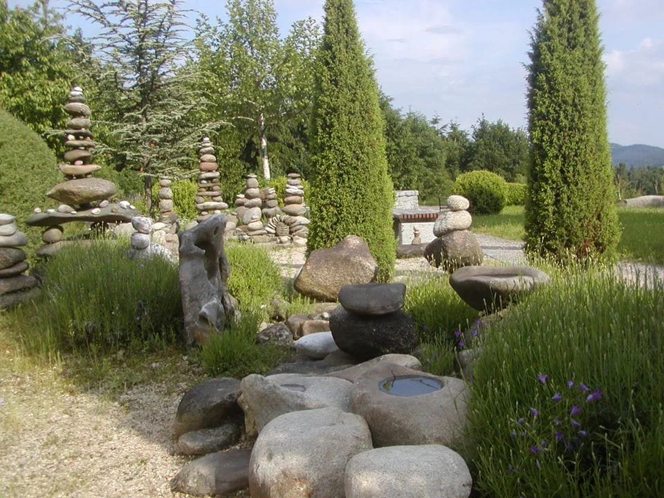 Steinskulpturen und Lavendel im Bibelgarten mit Zypressen und Blick auf bewaldete Hügel