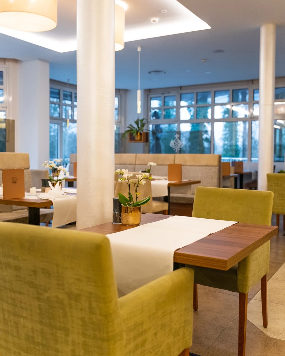 Restaurant mit gedeckten Tischen und grünen Polsterstühlen