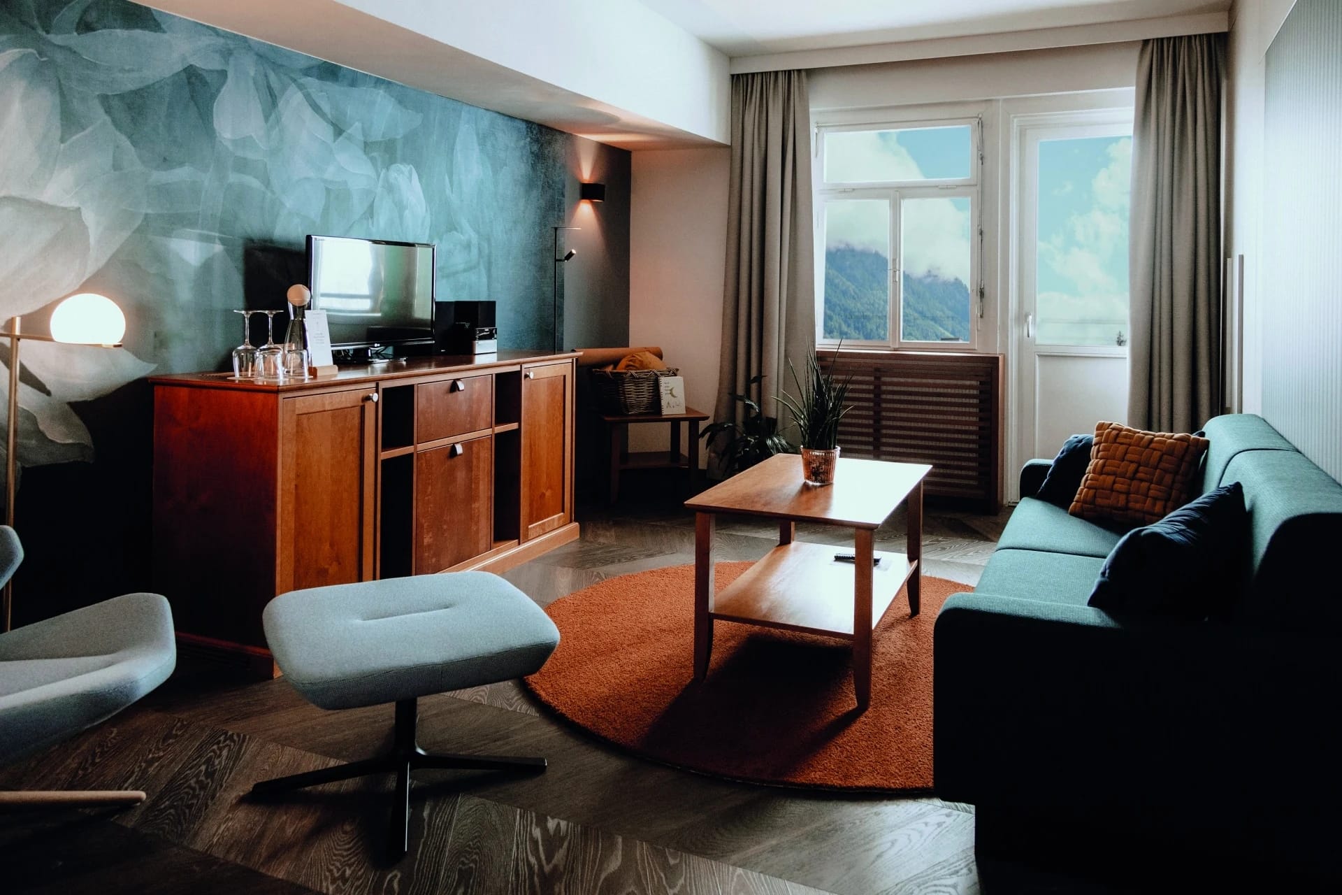 Wohnbereich der Auszeit Suite mit Sofa, dunkler Akzentwand und Fenster mit Bergblick