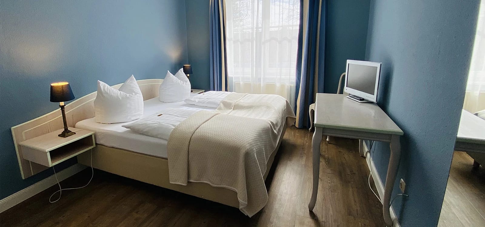 Blaues Zimmer mit Doppelbett und Schreibtisch