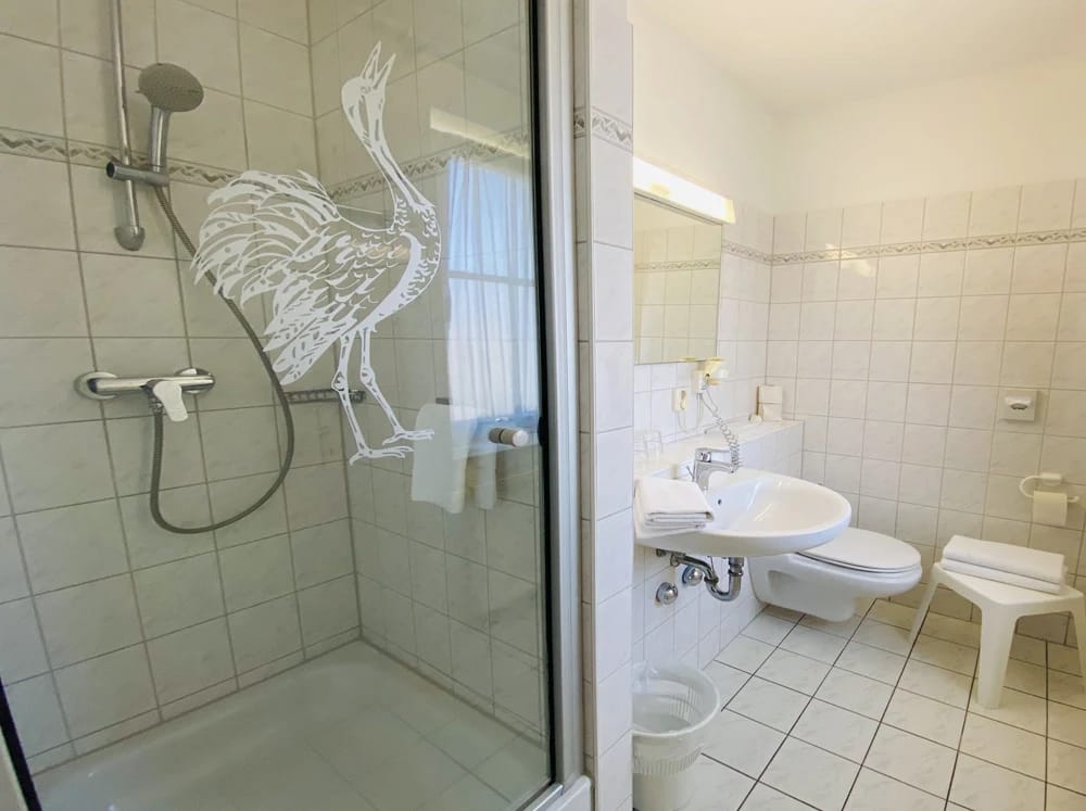 Badezimmer mit Dusche, Kranich-Motiv auf der Glaswand und Waschbecken