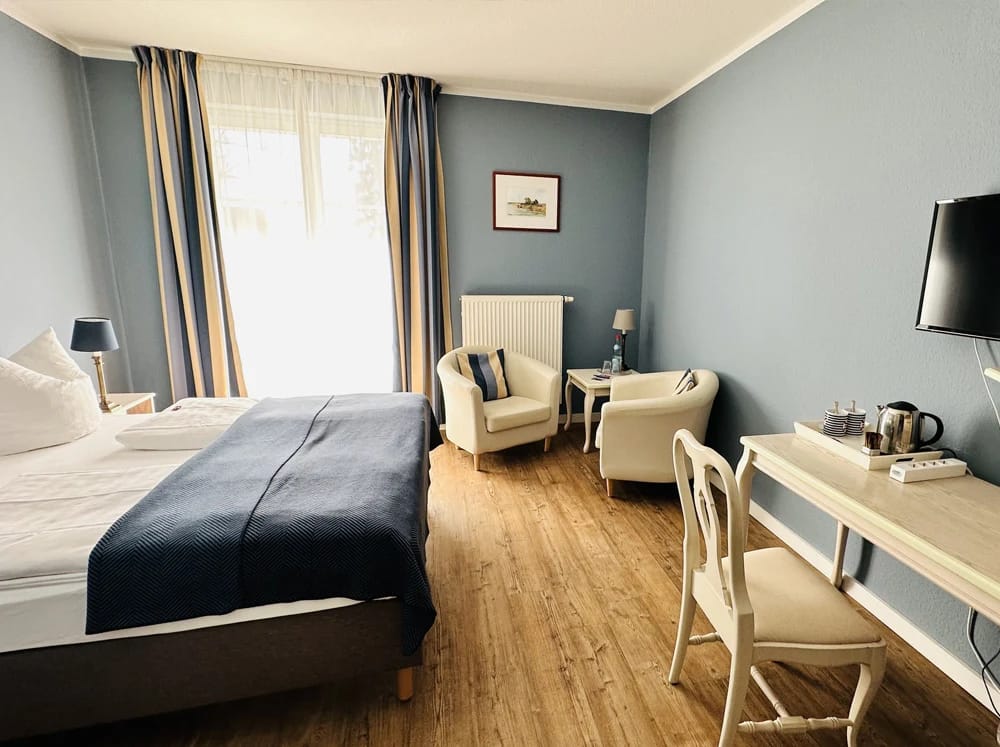 Zimmer mit Doppelbett, Sesselecke und Wandbildern