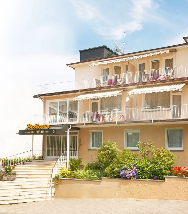 Frontansicht des Hotel Bellevue Bad Orb mit Eingangsbereich, Balkonen und blühendem Vorgarten