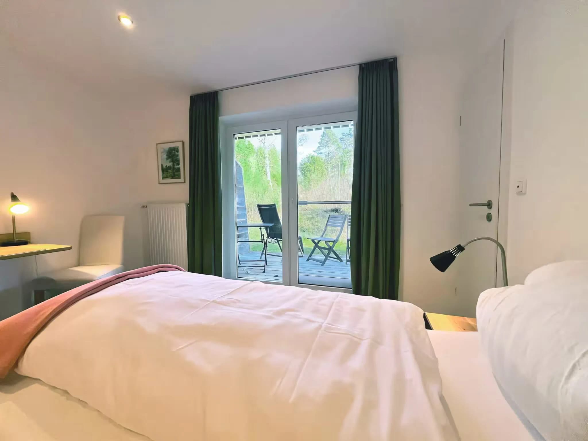 Doppelzimmer mit weißer Bettwäsche und Balkontür mit Sitzplatz