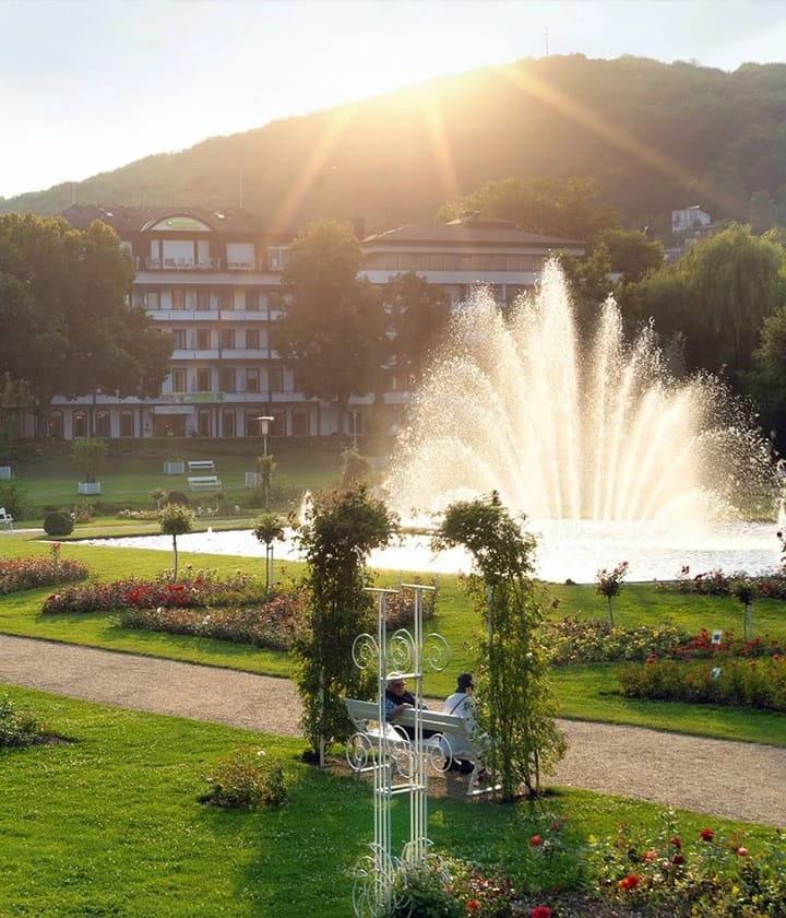 Kurpark in Bad Kissingen mit Springbrunnen, Blumenbeeten und historischem Gebäude im Abendlicht