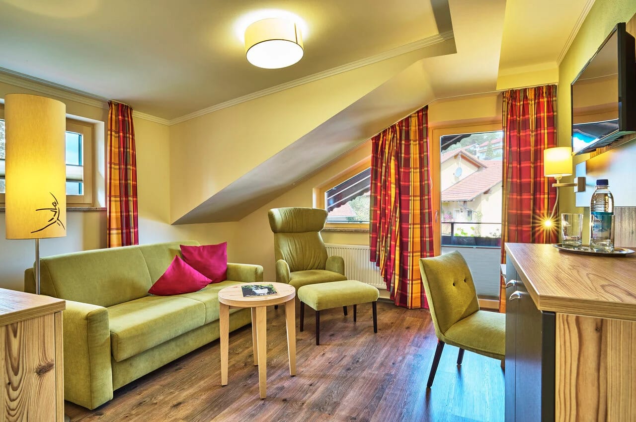 Wohnbereich eines Appartements mit grünem Sofa und Sitzgruppe