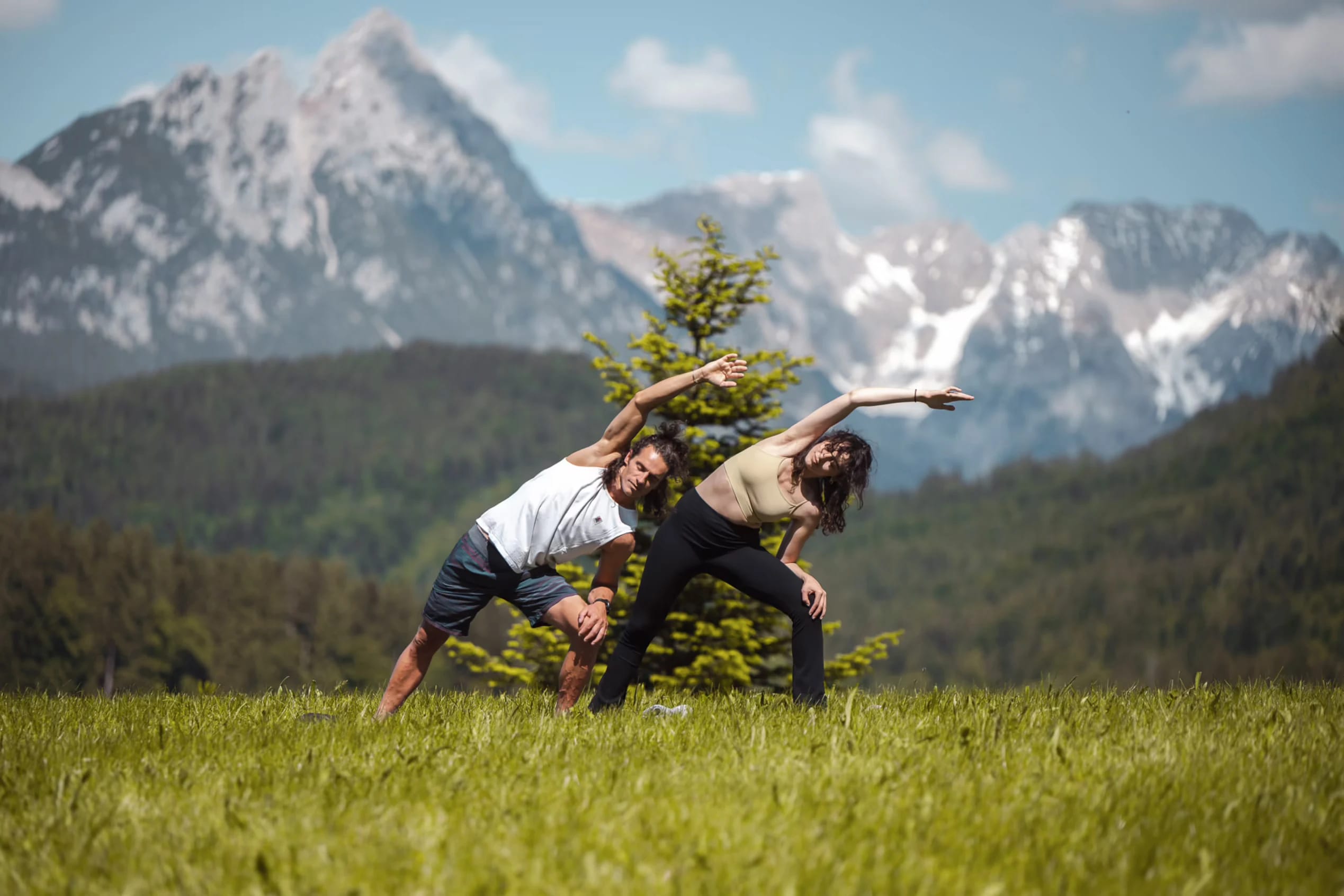 Yogaraum mit Holzboden, bodentiefen Fenstern und Blick auf Wiese und Wald