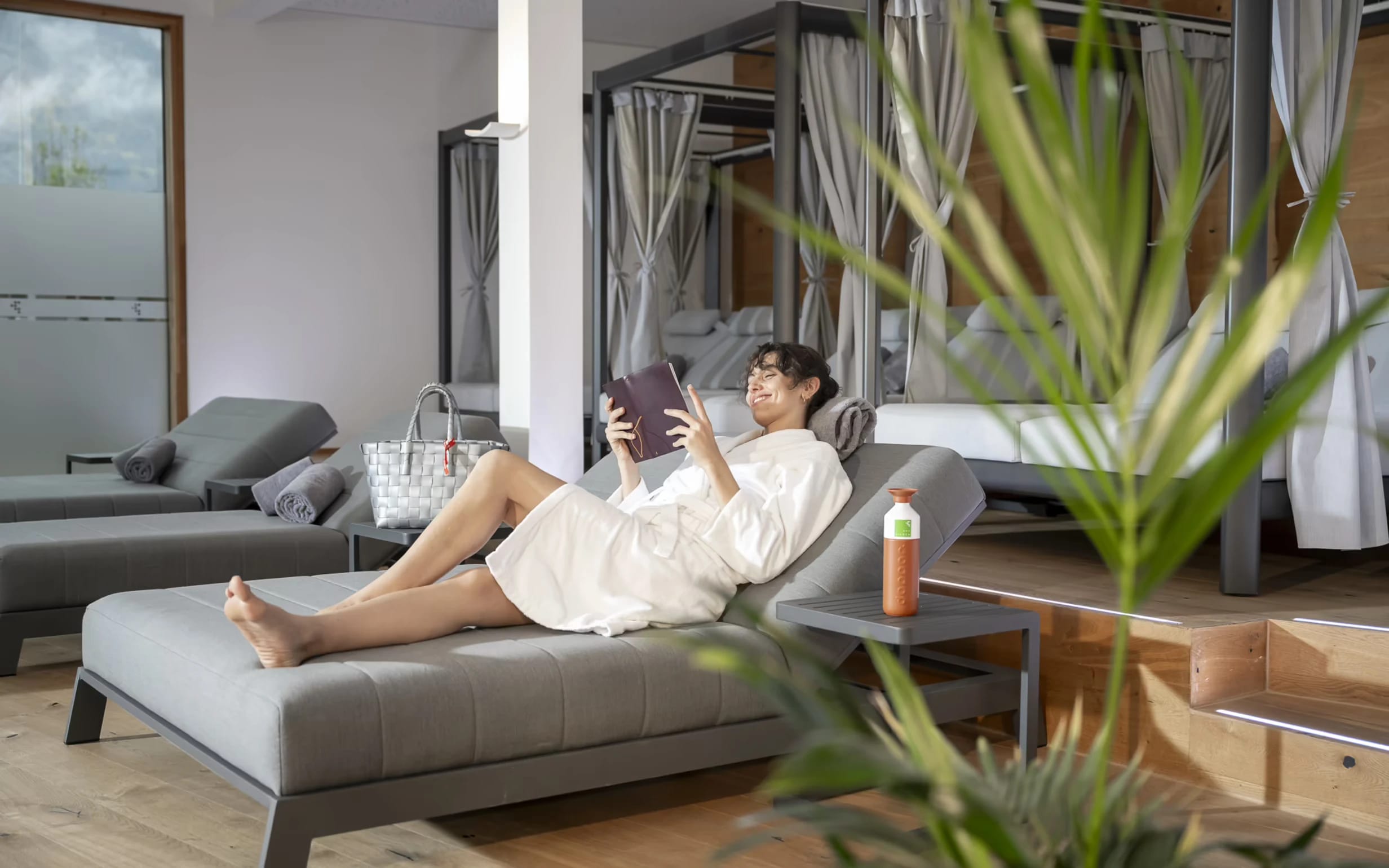 Ruheraum mit grünen Relaxliegen, Holzboden und Vorhängen