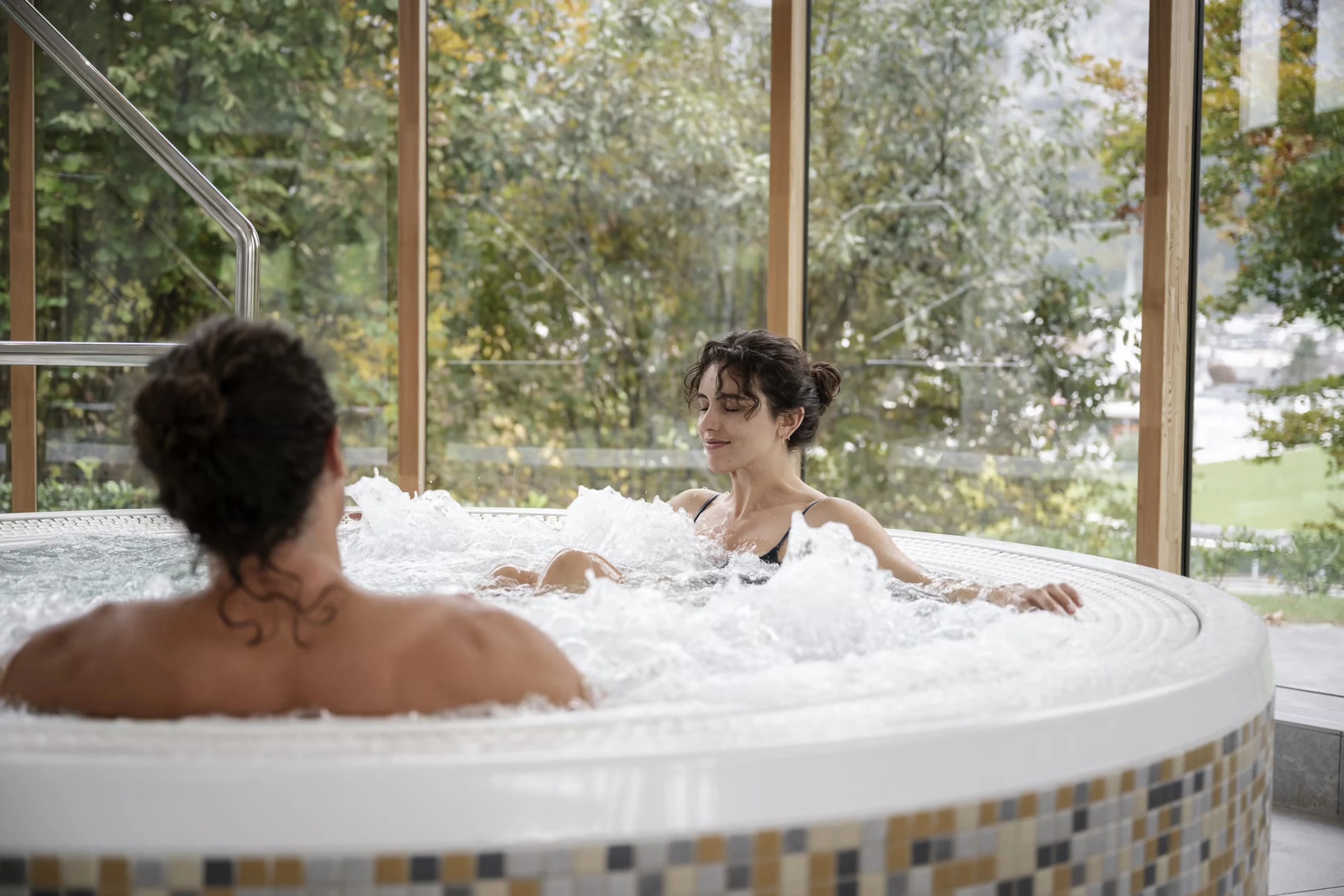 Runder Whirlpool am Fenster mit Blick auf herbstliche Bäume