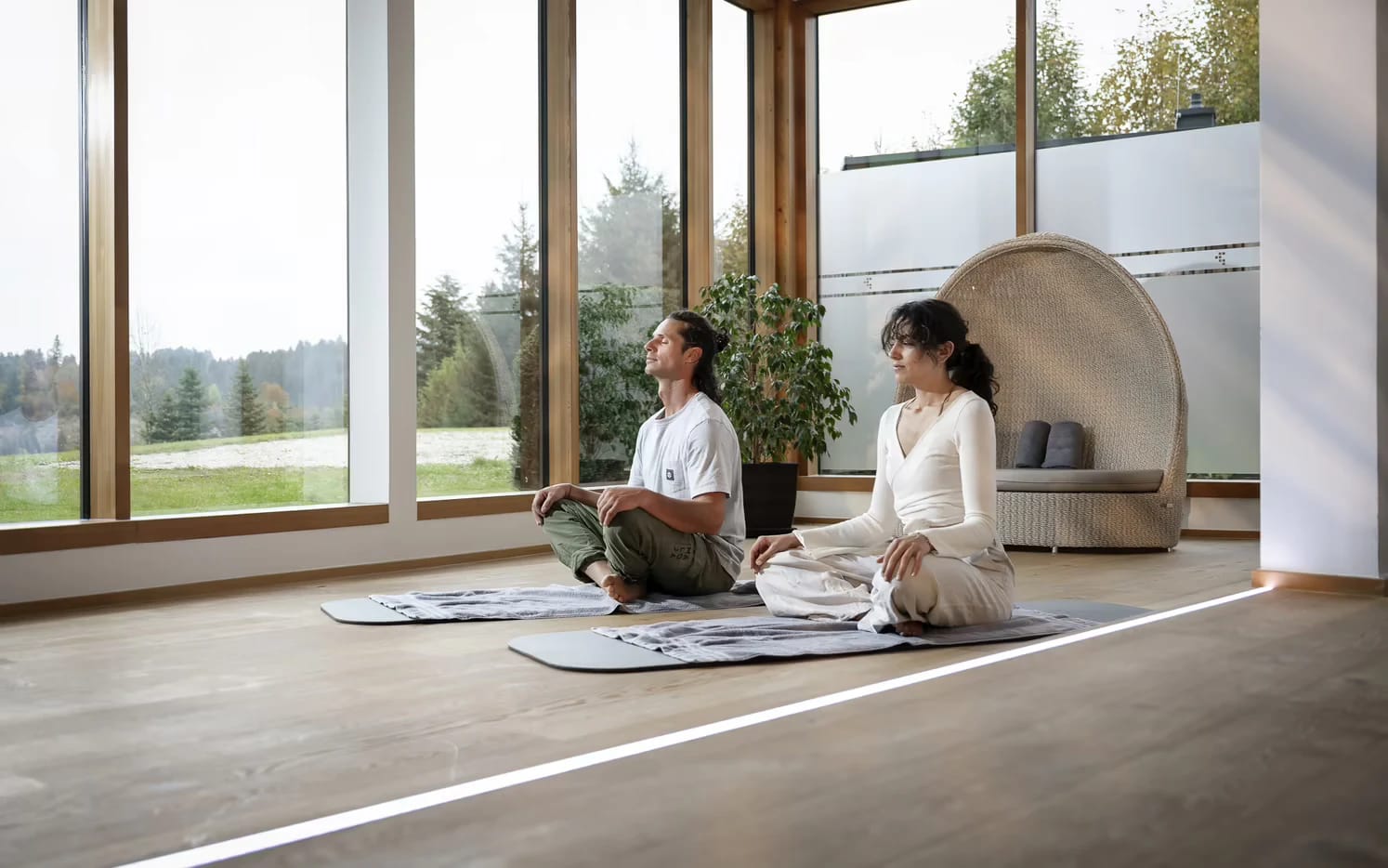 Heller Yoga- und Bewegungsraum mit raumhohen Fenstern und Blick ins Grüne