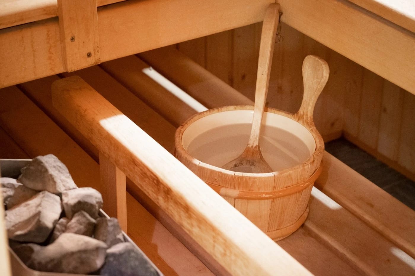 Saunainnenraum mit Holzkübel, Schöpfkelle und Saunasteinen