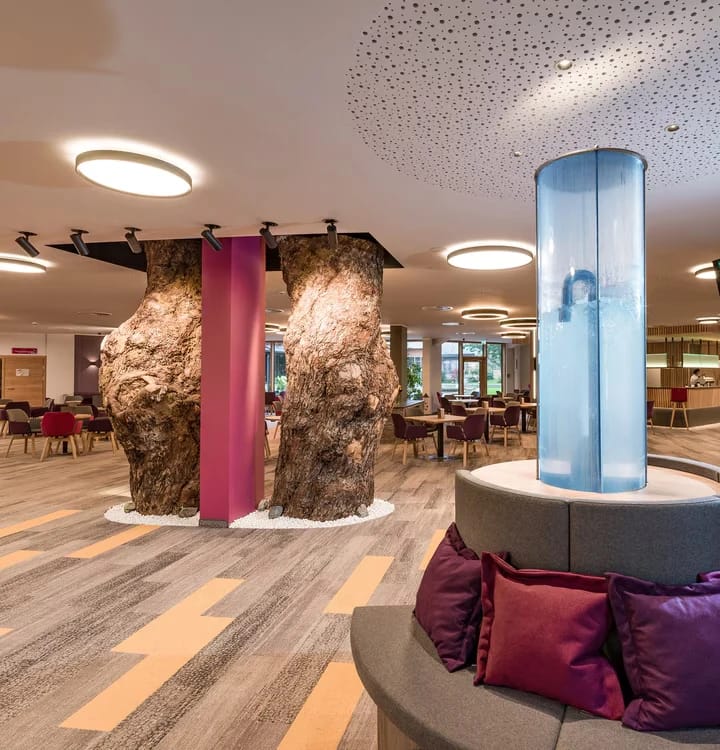 Lobby mit Baumstamm-Säulen, Wassersäule und Sitzbereich