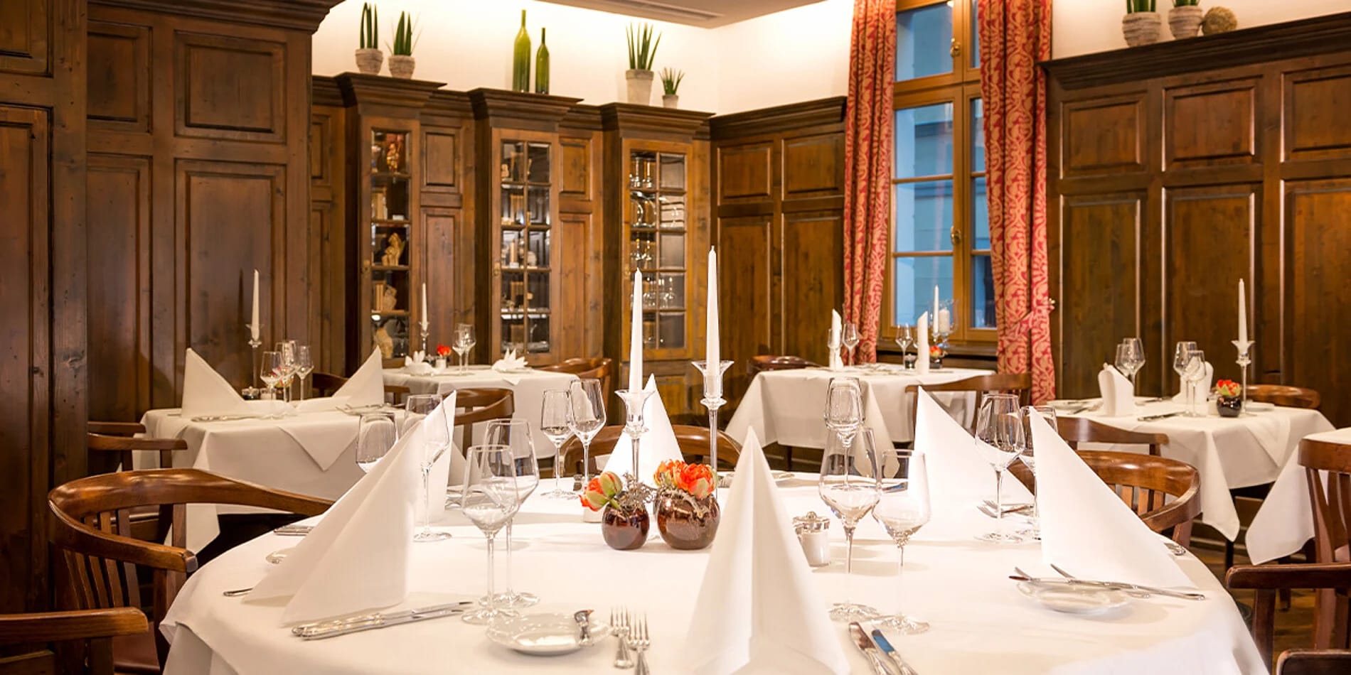 Restaurant mit weiß eingedeckten Tischen und Holzvertäfelung