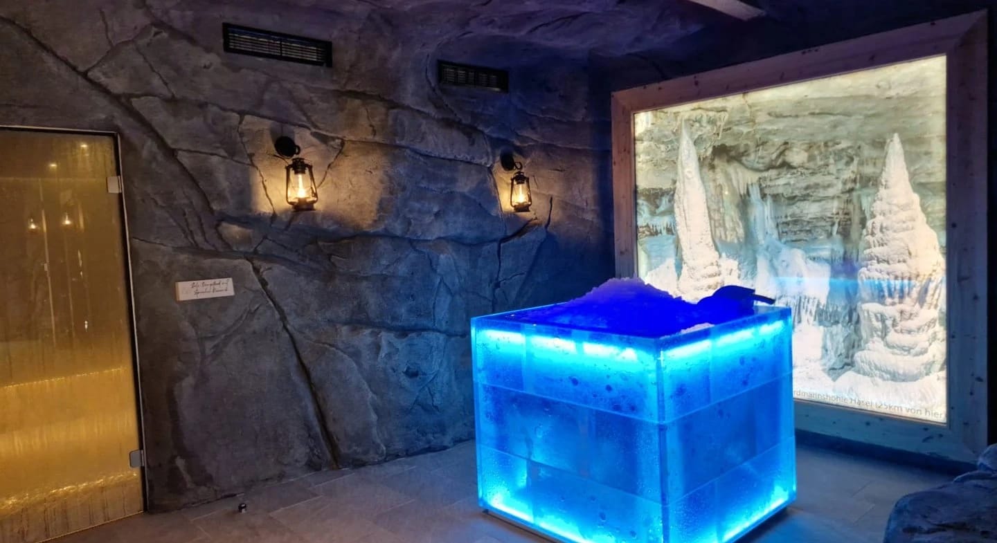Eisbrunnen mit blau beleuchtetem Eisblock im Felsengang des Saunabereichs