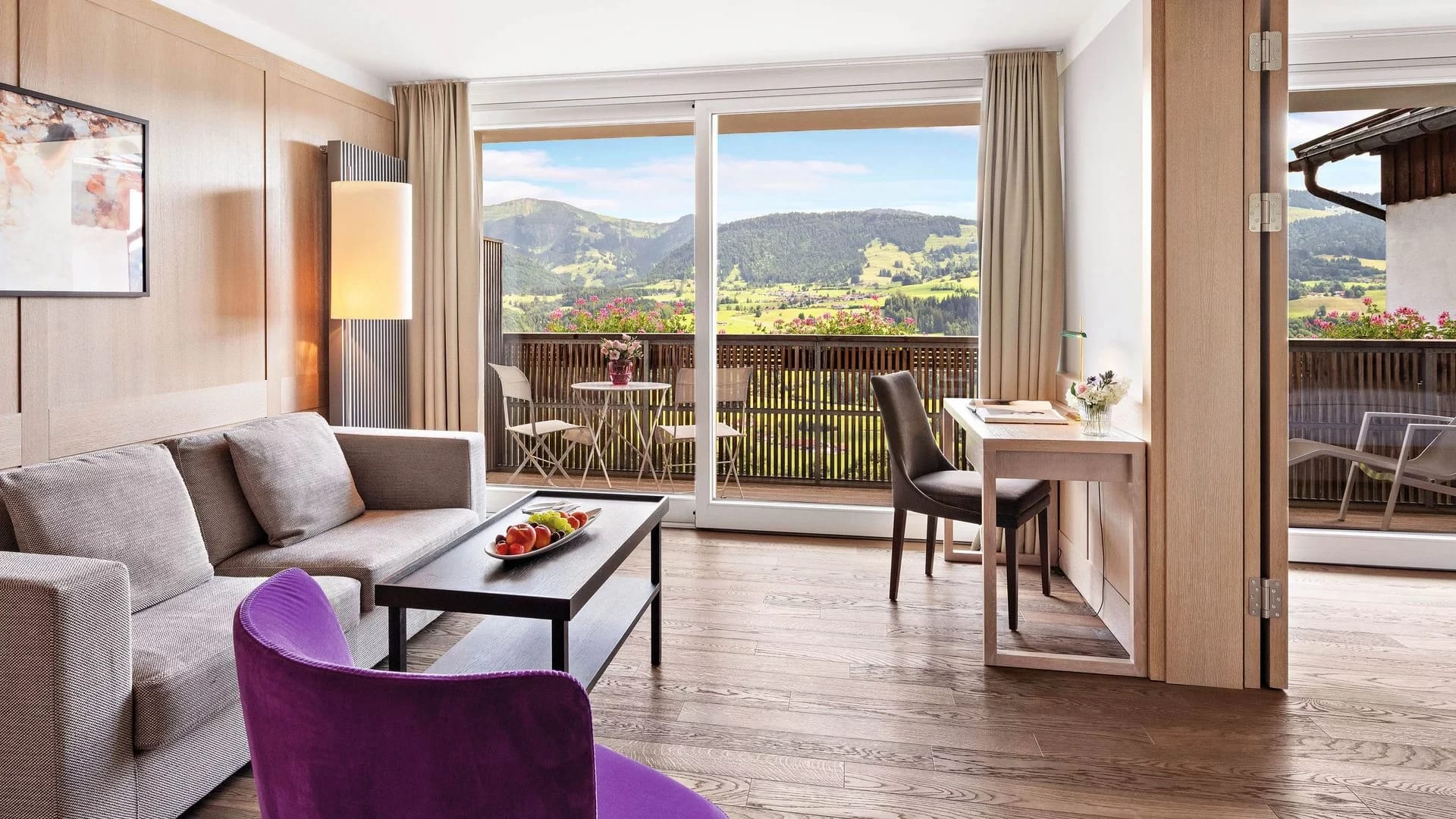 Wohnbereich einer Juniorsuite mit Sofa, Sessel und Balkontür mit Bergblick