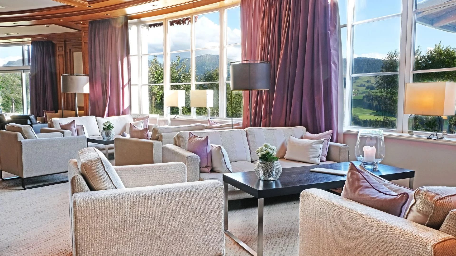 Helle Panoramahalle mit Sesseln und Sofas an großen Fenstern mit Blick auf die Berge