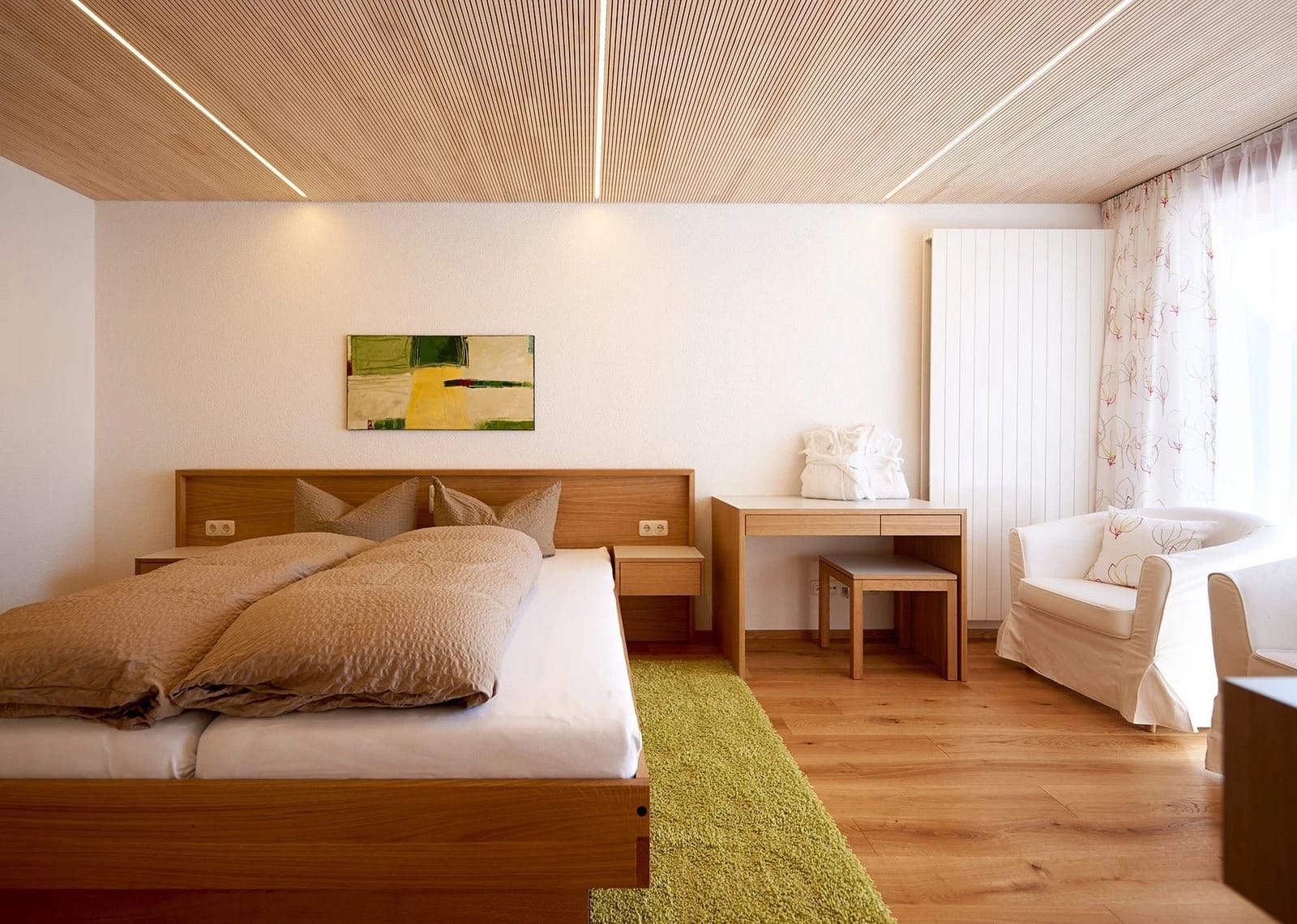 Zimmerbereich mit Tagesbett an der Holzwand und angrenzendem Bad mit rotem Waschtisch
