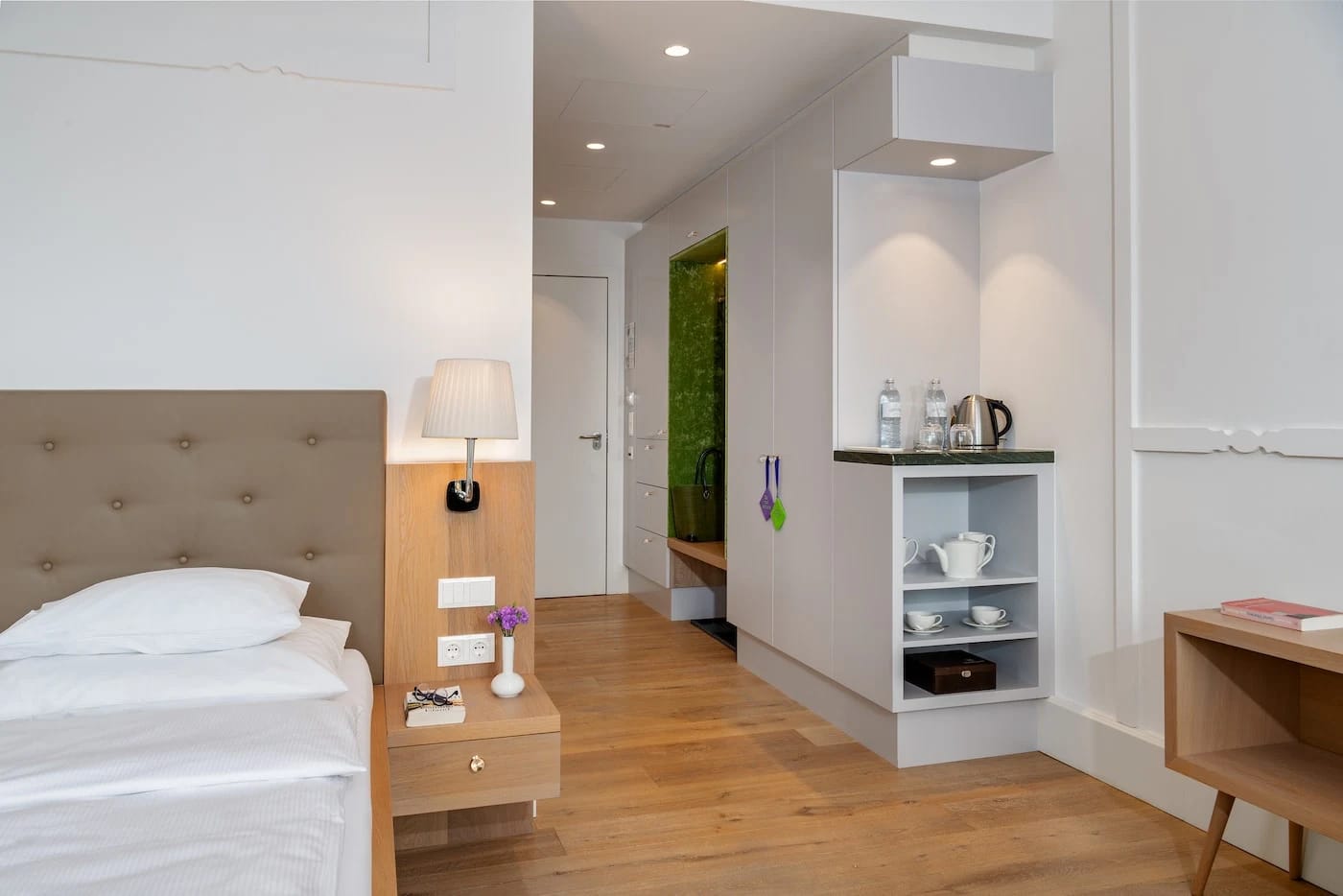 Einzelzimmer mit Bett, Nachttisch, Teestation und Holzboden