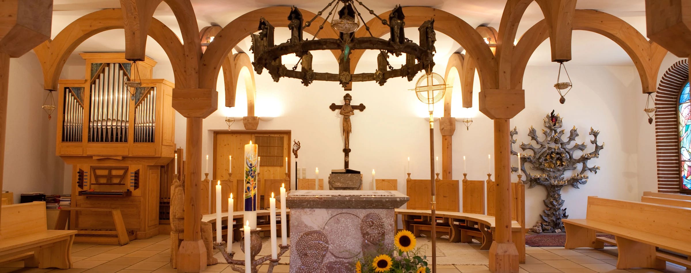 Klosterkirche mit Altar, Kruzifix, Orgel und großem schmiedeeisernem Kerzenleuchter