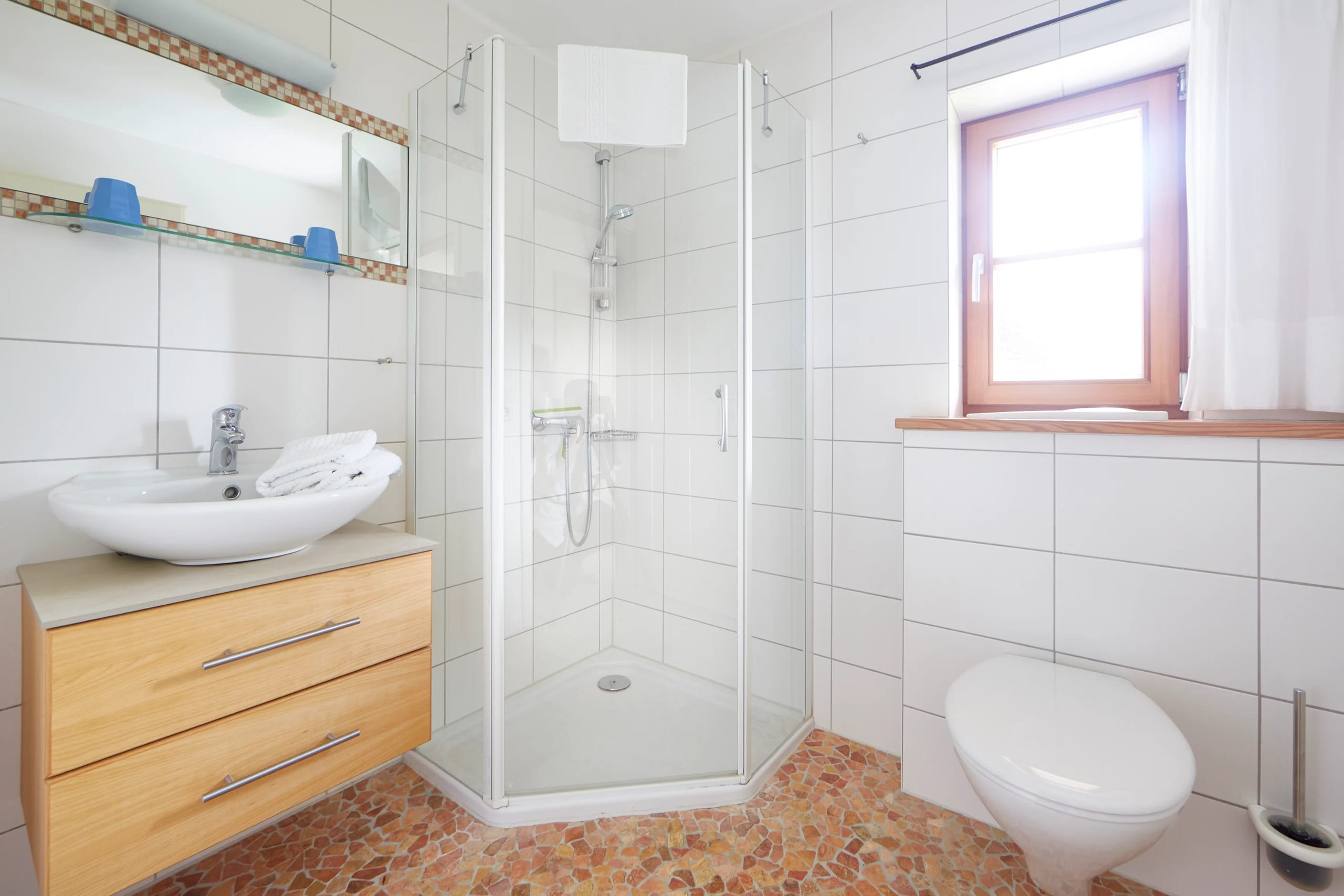 Badezimmer mit Eckdusche, Waschtisch aus Holz und Fenster