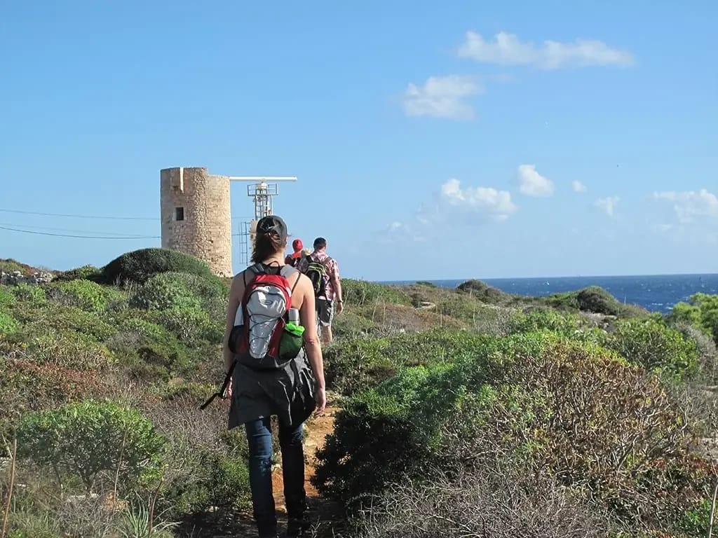 Fastenwandergruppe mit Rucksäcken auf einem Wanderweg bei einem Steinturm auf Mallorca