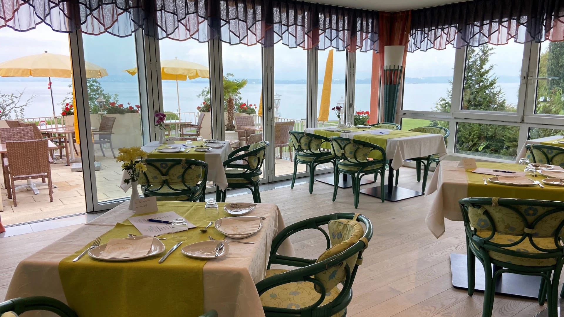 Frühstücksraum mit gedeckten Tischen und Fensterfront mit Blick auf den Bodensee