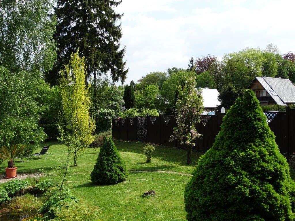 Gartenanlage mit Rasen, Koniferen und blühenden Sträuchern
