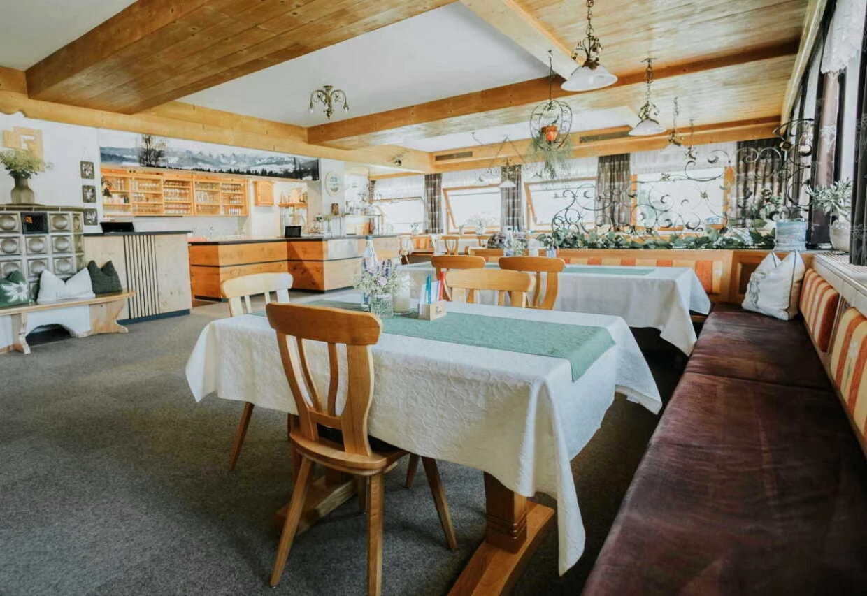 Heller Speisesaal mit eingedeckten Tischen, Holzstühlen und langer Sitzbank