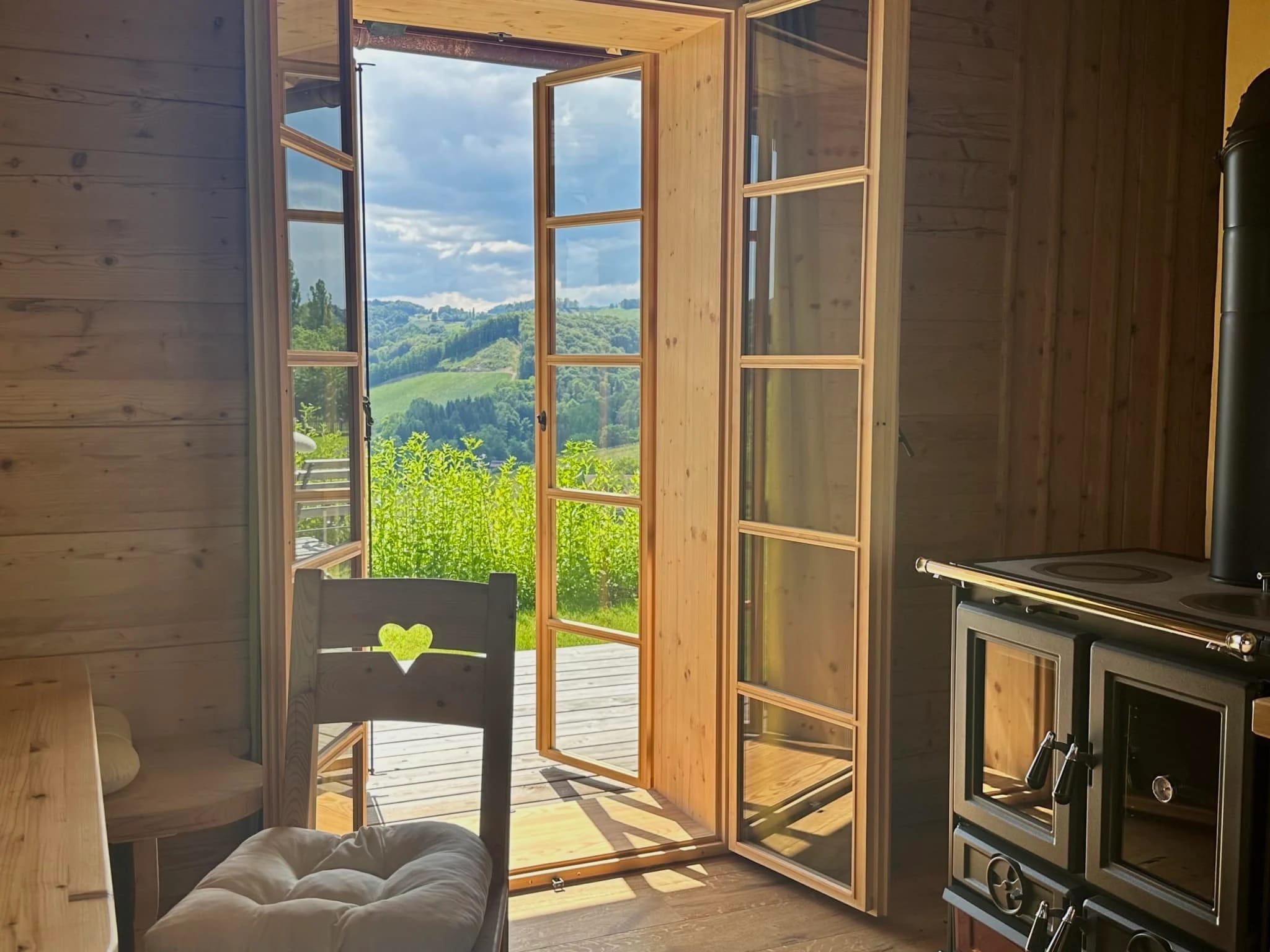 Zimmer mit altem Holzherd und offener Tür zur Terrasse mit Ausblick
