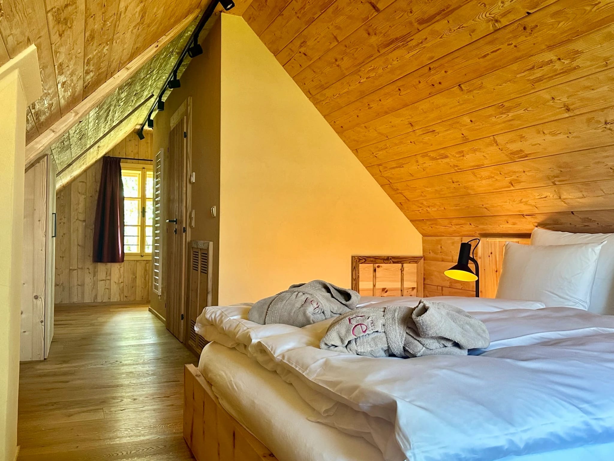 Gemütliches Dachzimmer mit heller Holzverkleidung und Doppelbett