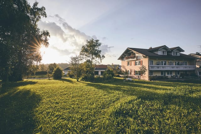 Hotelgebäude mit Balkonen im Abendlicht, davor eine große Wiese mit Bäumen